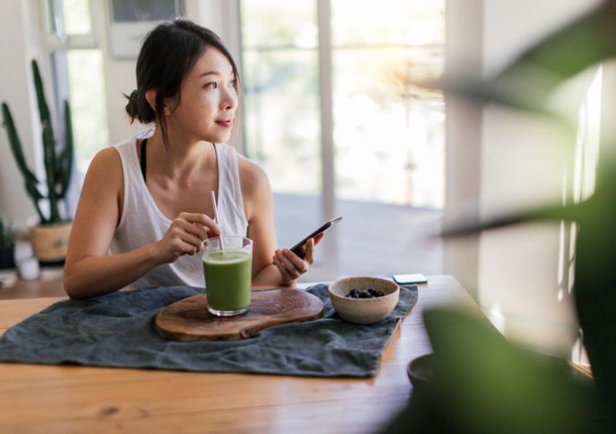 young woman with IBS having green drink