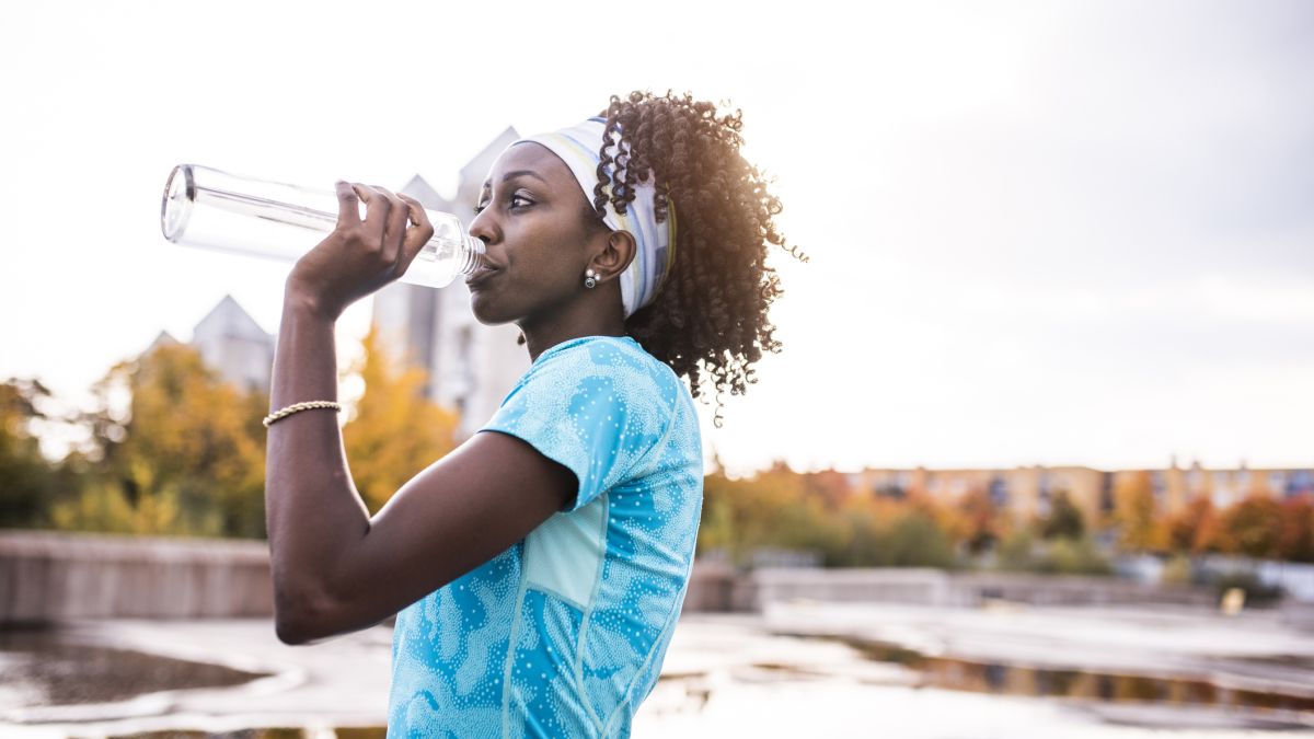 woman drinking water outside to avoid dehydration