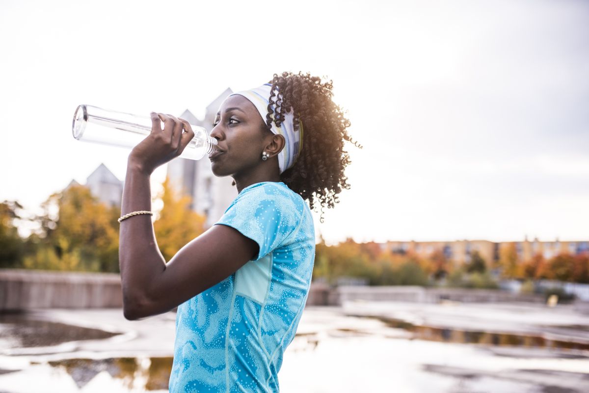 woman drinking water outside to avoid dehydration