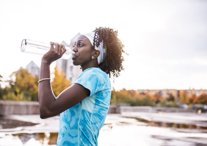 woman drinking water outside to avoid dehydration