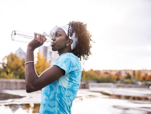 woman drinking water outside to avoid dehydration