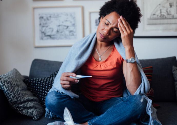 Woman sitting on coach with thermometer
