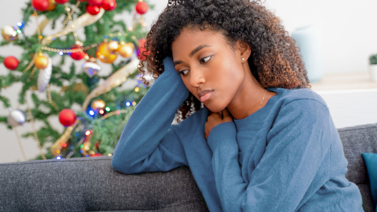 woman looking serious sitting near Christmas tree
