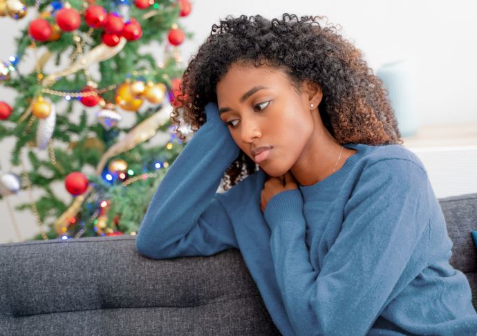 woman looking serious sitting near Christmas tree