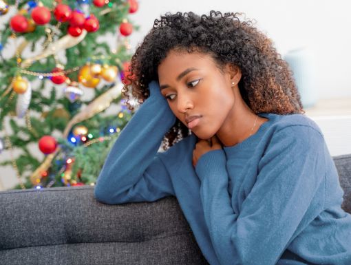 woman looking serious sitting near Christmas tree