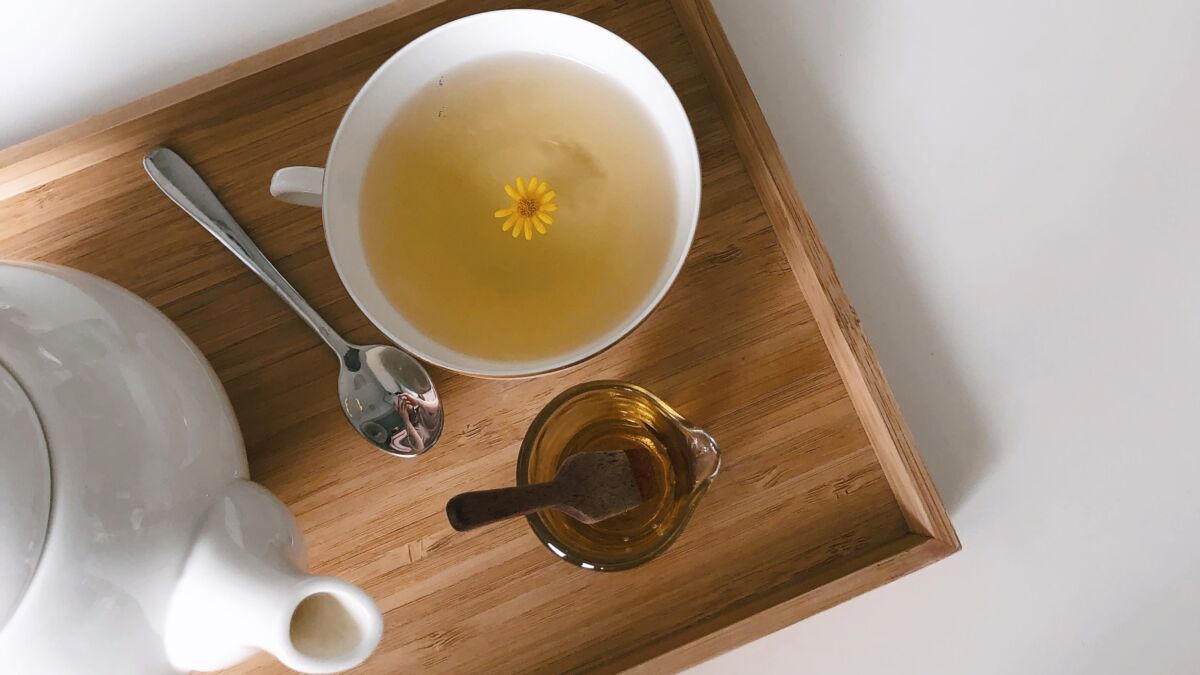 cup of tea with honey and tea kettle on tray