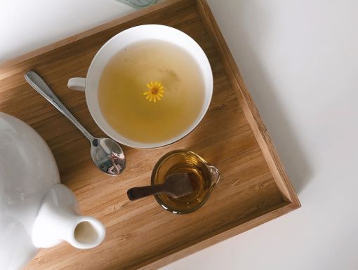 cup of tea with honey and tea kettle on tray