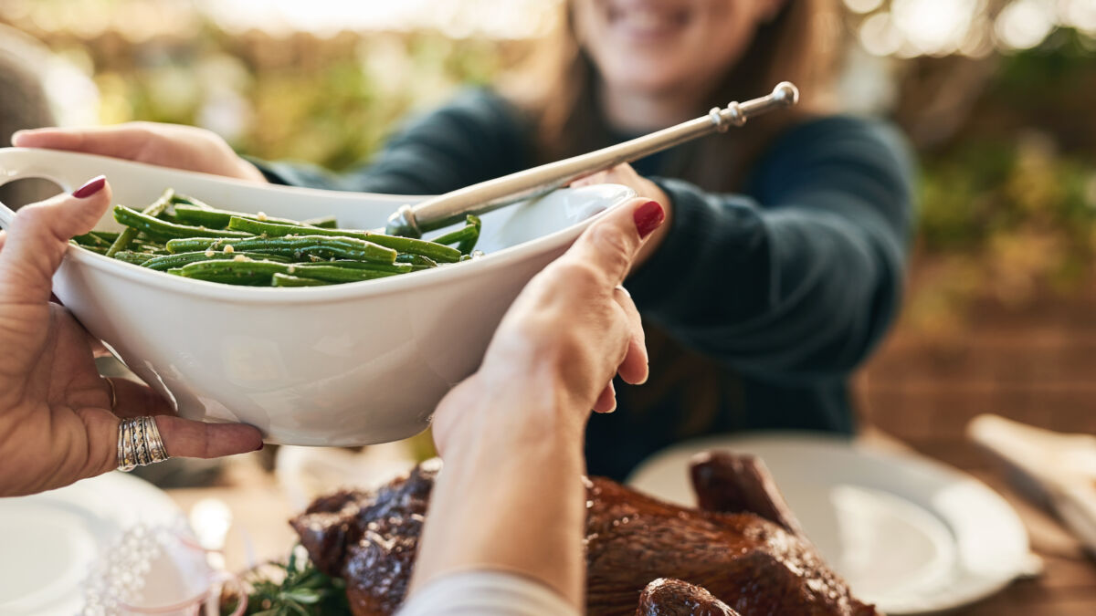 Woman passing bowl of green beans to another person