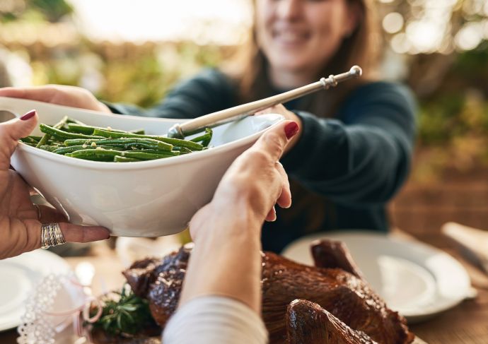 Woman passing bowl of green beans to another person