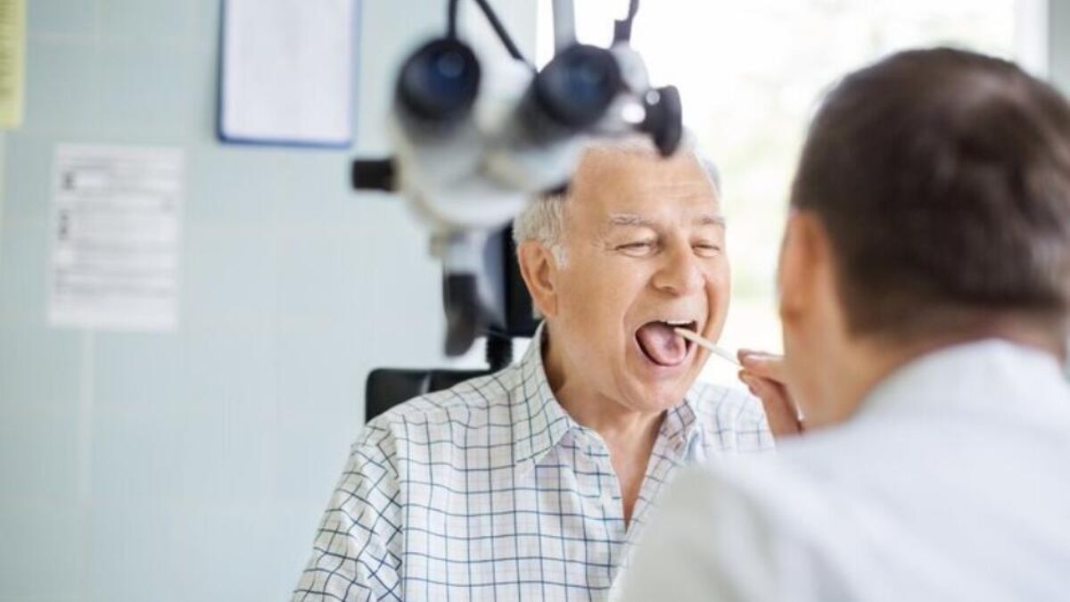 Patient sitting in a chair, having their throat looked at by a doctor
