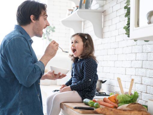 Dad feeding daughter