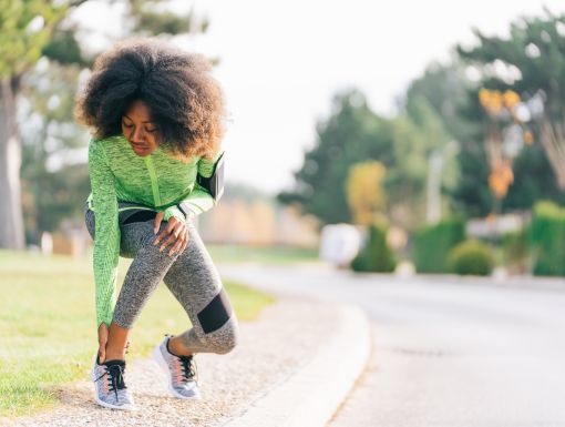 woman grabbing ankle after stopping in middle of a run
