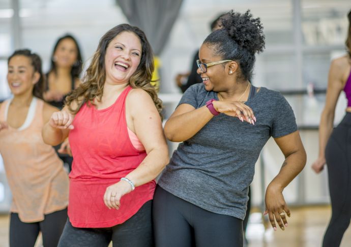 Two older women dancing together at a workout class