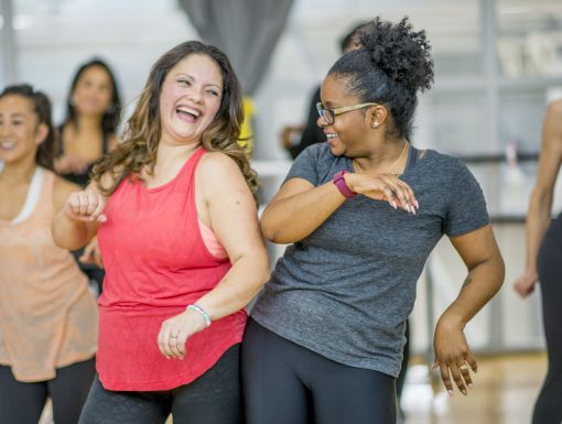 Two older women dancing together at a workout class