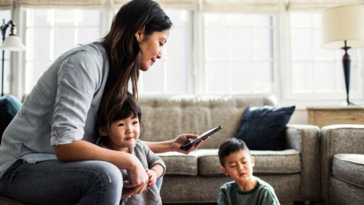 woman with small children looking at cell phone