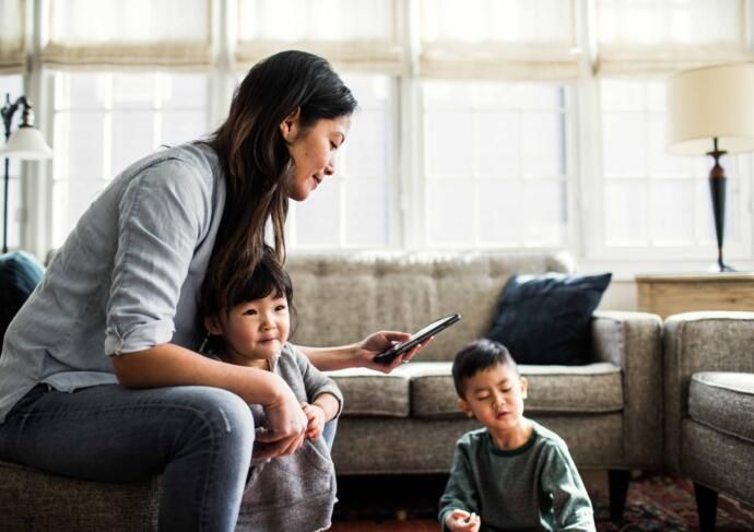 woman with small children looking at cell phone
