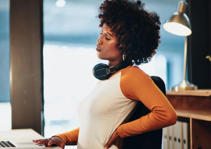 Woman at desk holding lower back 2