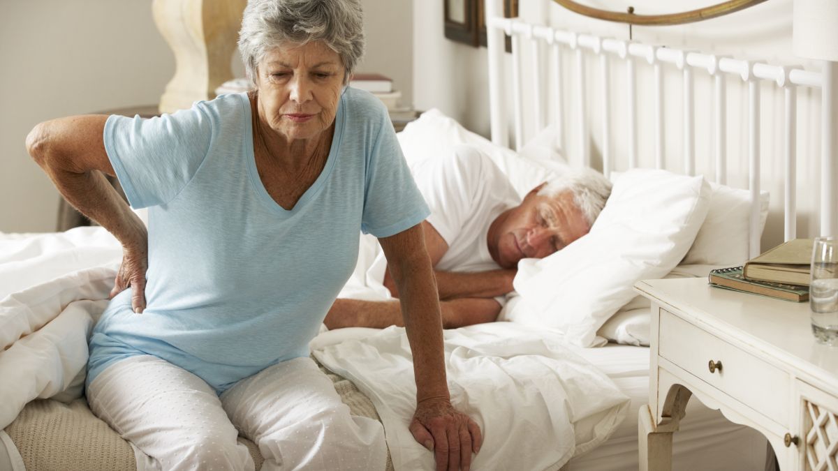Woman holding back while getting out of bed