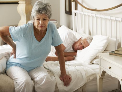 Woman holding back while getting out of bed