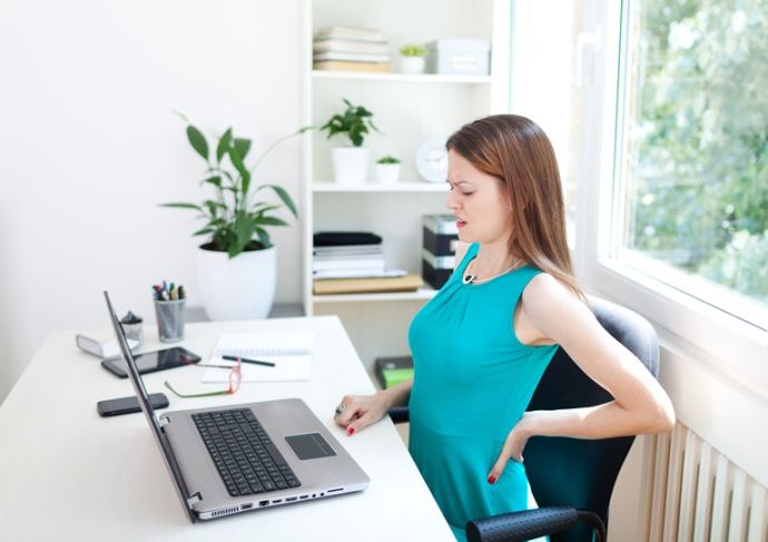 woman at desk with pain in her back