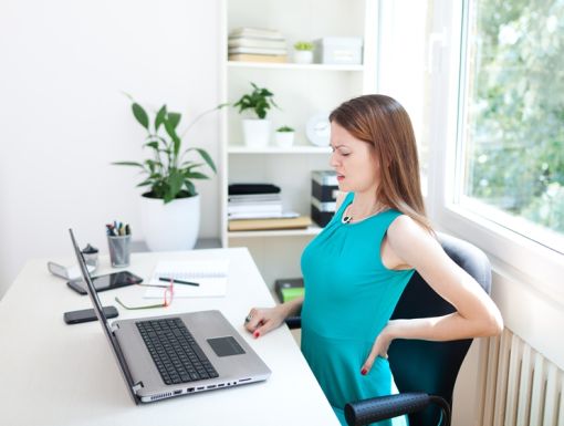 woman at desk with pain in her back