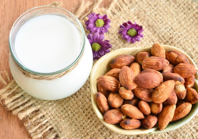 Glass jar of plant-based milk with bowl of almonds next to it