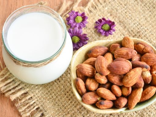 Glass jar of plant-based milk with bowl of almonds next to it