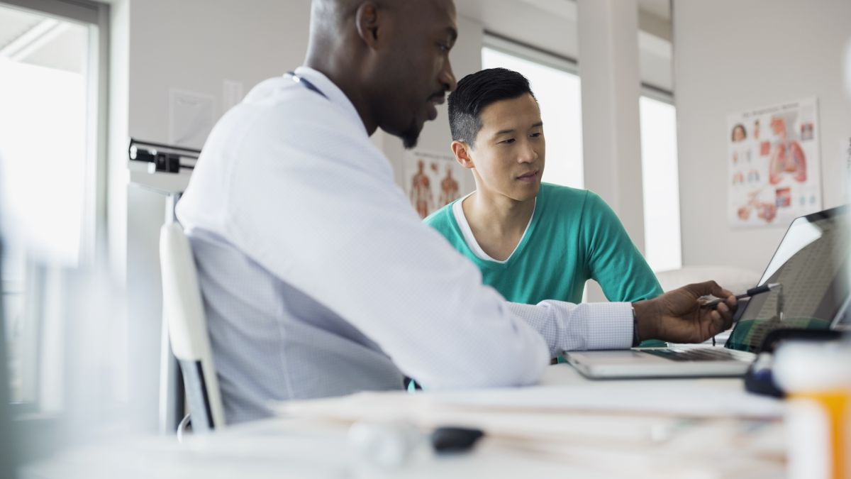 Man talking to doctor reviewing records on computer