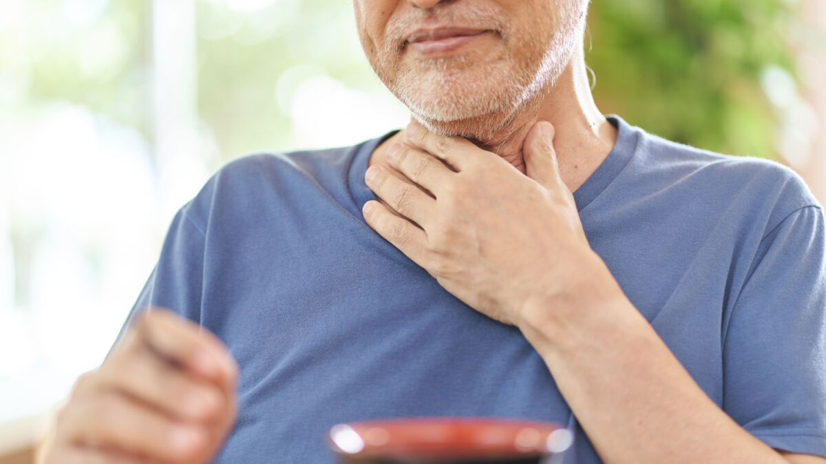 Older man holding his throat with one hand