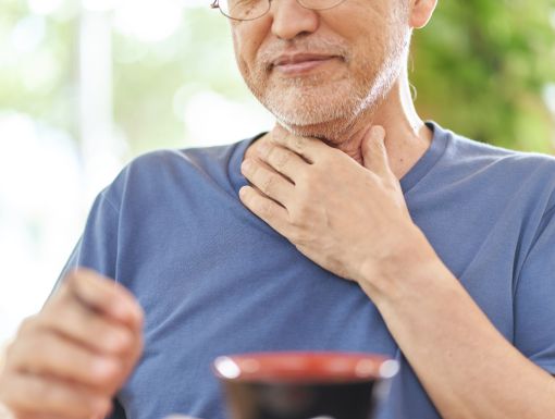 Older man holding his throat with one hand