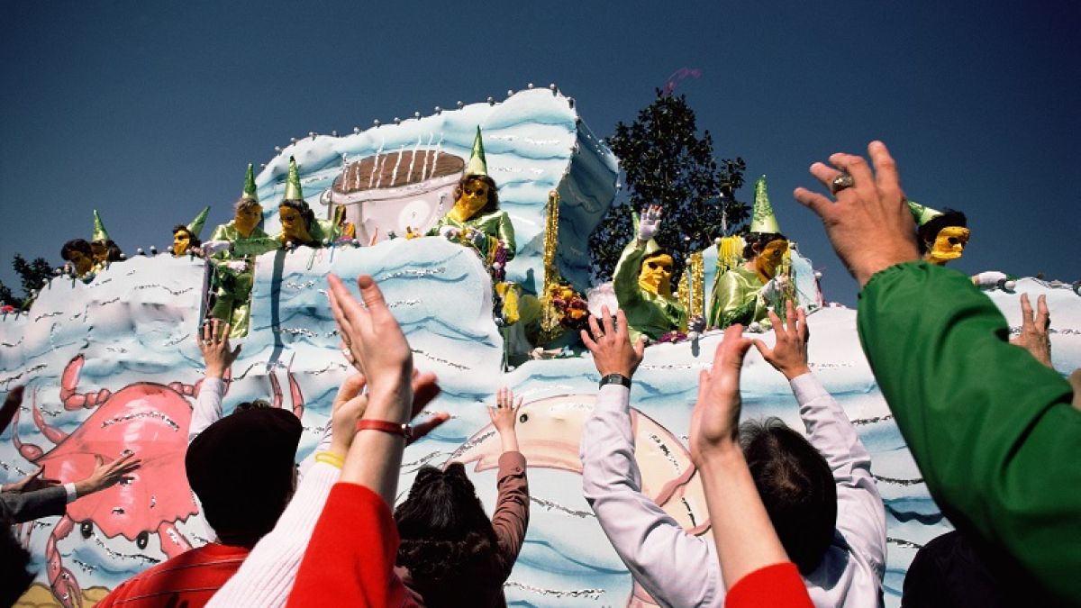 People reaching for beads from a Mardi Gras float