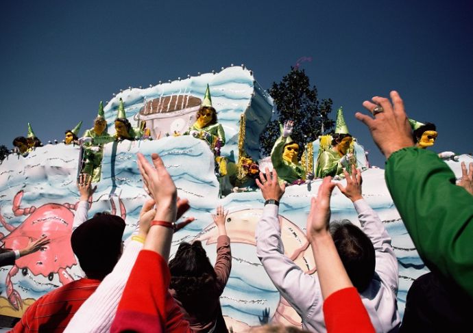 People reaching for beads from a Mardi Gras float