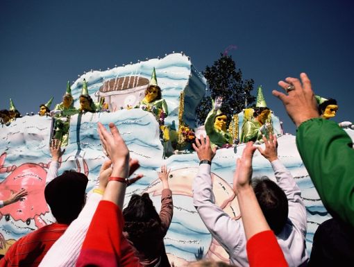 People reaching for beads from a Mardi Gras float