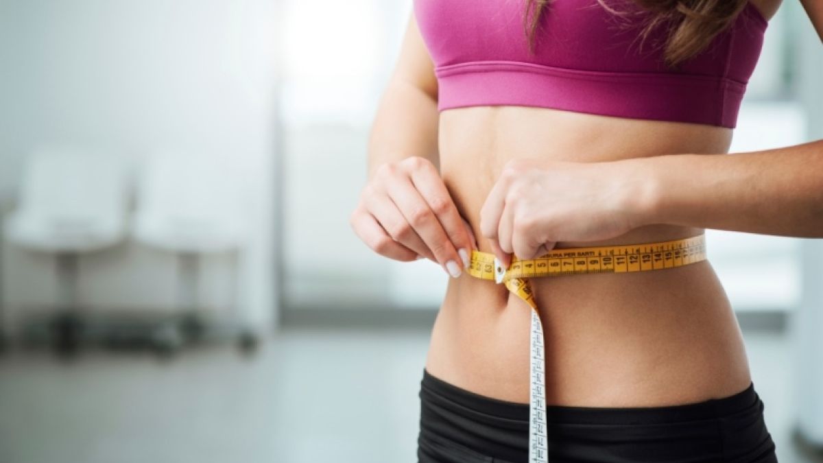 Woman measuring her waist with a tape measure