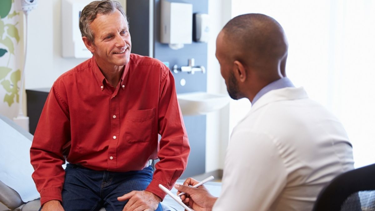 Male Patient And Doctor Consulting In Hospital Room