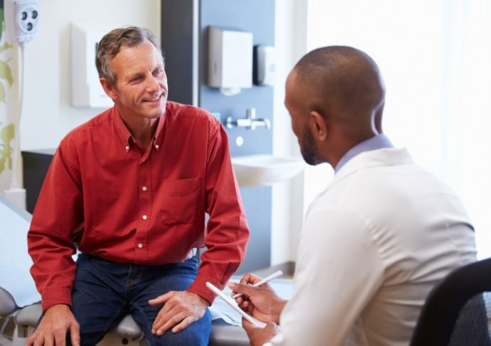 Male Patient And Doctor Consulting In Hospital Room
