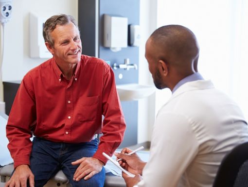 Male Patient And Doctor Consulting In Hospital Room