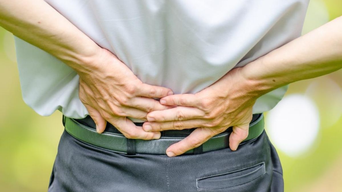 man suffering from spinal stenosis grabbing lower back in pain
