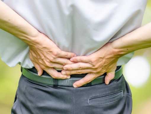 man suffering from spinal stenosis grabbing lower back in pain