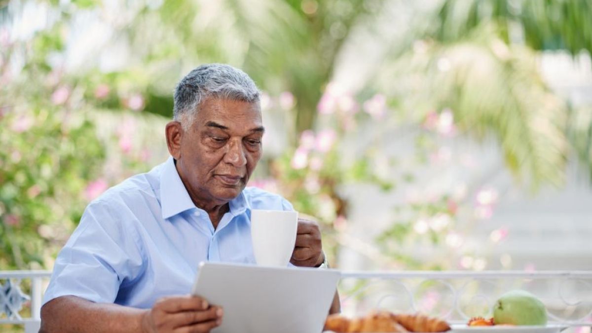 man reading outside while enjoying a meal