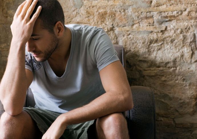 man With Hand on Head leaning against rock wall