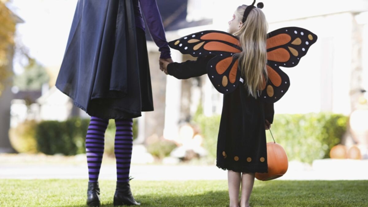 girl dressed as a butterfly holding parent's hand on Halloween
