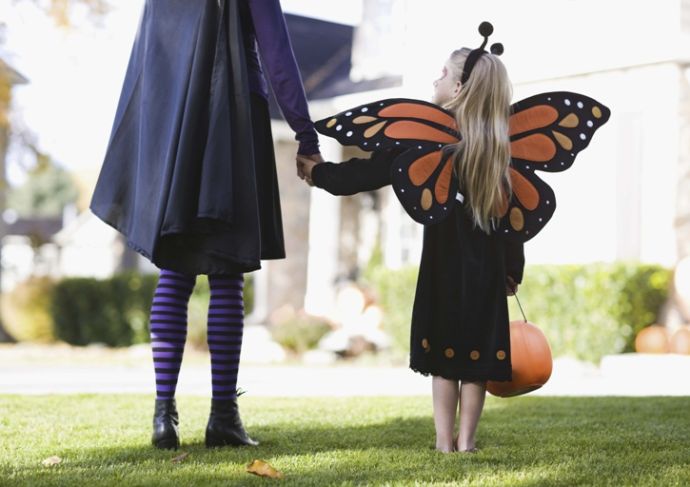 girl dressed as a butterfly holding parent's hand on Halloween