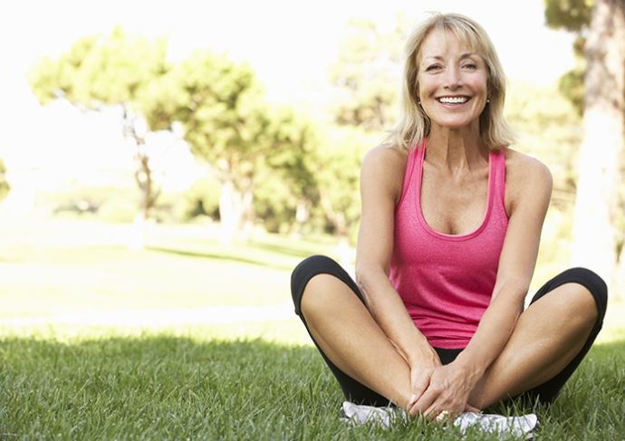 smiling older woman sitting outside in the grass