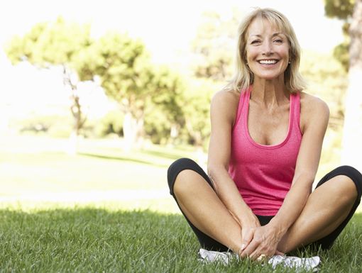 smiling older woman sitting outside in the grass