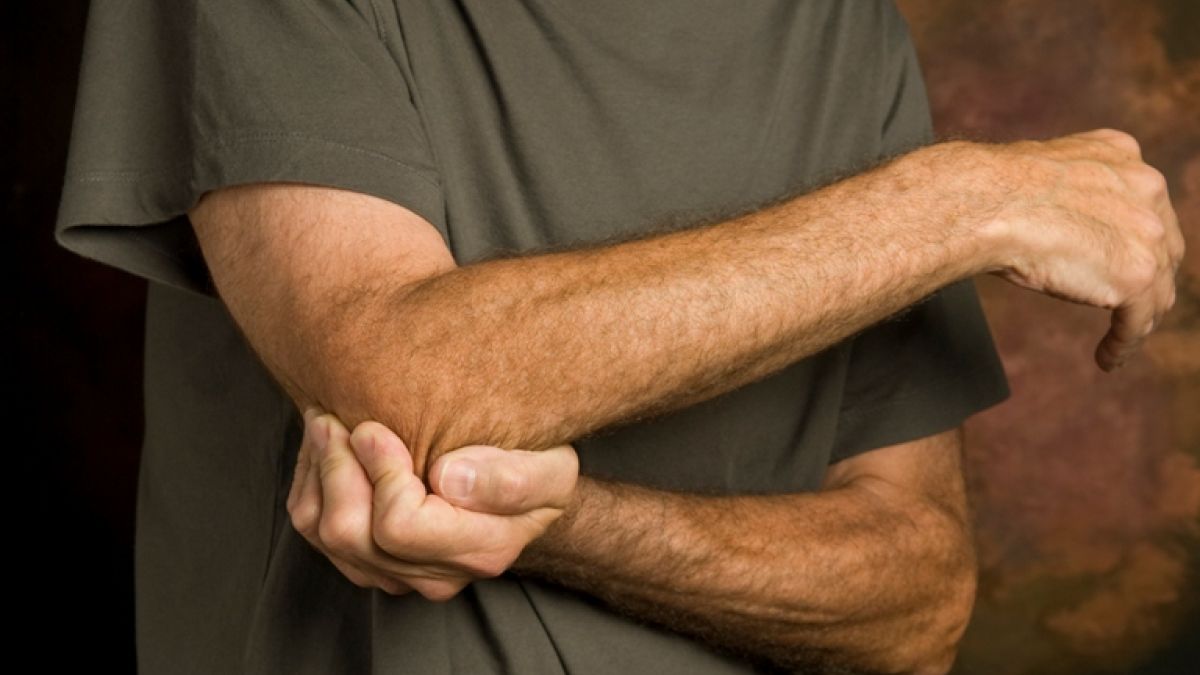 man holding arm due to pain caused by cubital tunnel syndrome