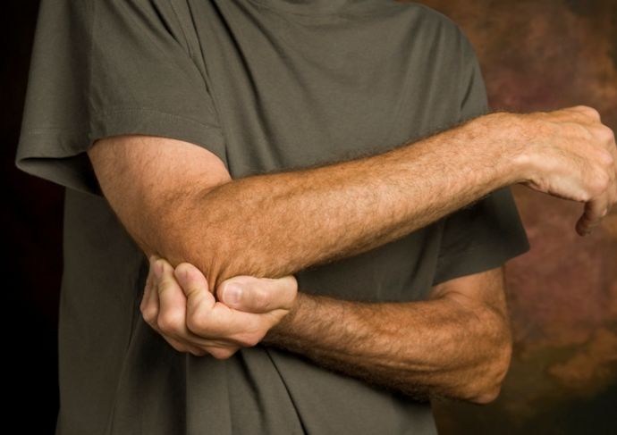 man holding arm due to pain caused by cubital tunnel syndrome