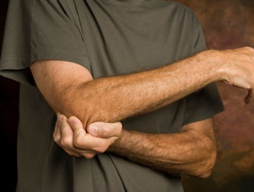 man holding arm due to pain caused by cubital tunnel syndrome