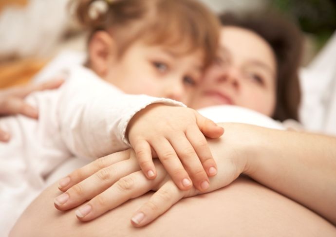 Pregnant woman with her first born touching her pregnant belly