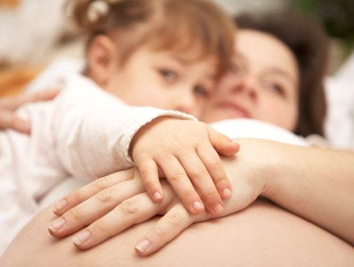 Pregnant woman with her first born touching her pregnant belly